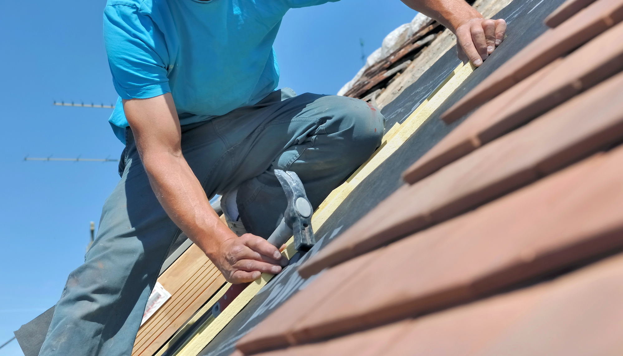 close on a worker holding a hammer and renoving a roof of a house